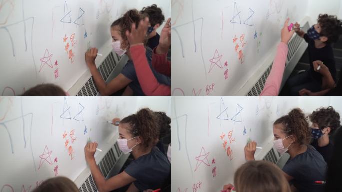 多民族小学生在白墙上画画