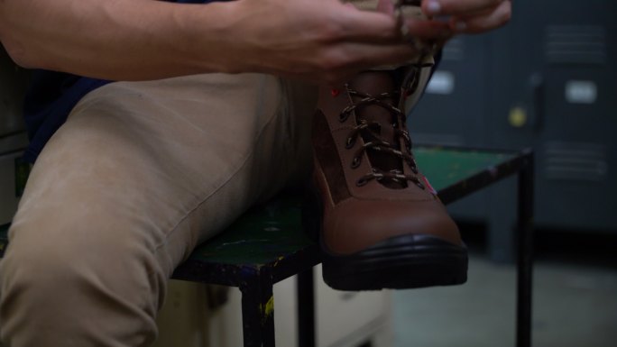 无法辨认的男子穿上工作靴并试穿的特写镜头