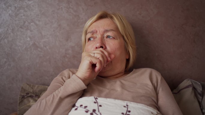 老年妇女患流感强烈咳嗽生病躺在床上