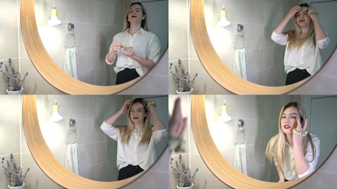 一位白人女商人，一边化妆，一边对着浴室镜子观察自己