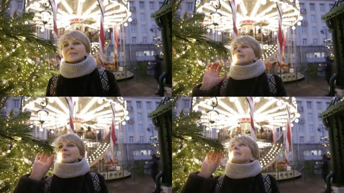 迷人的成熟女性，一名游客，在圣诞节期间在大城市享受节日装饰，探索带旋转木马的公共公园。