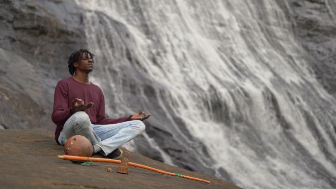 非洲男子冥想瀑布打坐静心感受大自然
