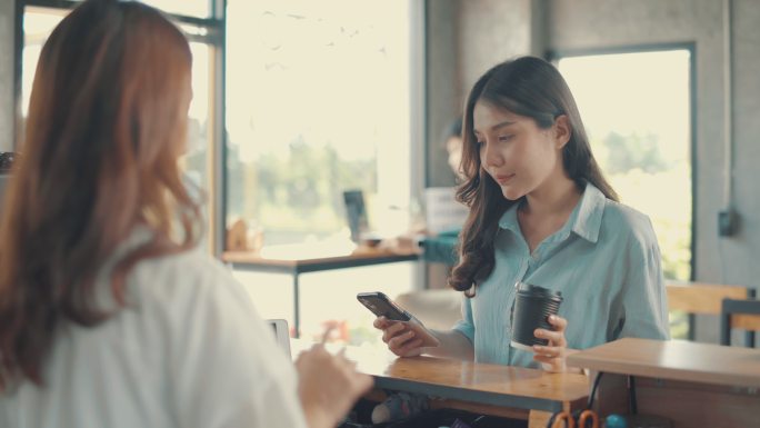 亚洲女子用手机支付咖啡，用无接触二维码购买咖啡