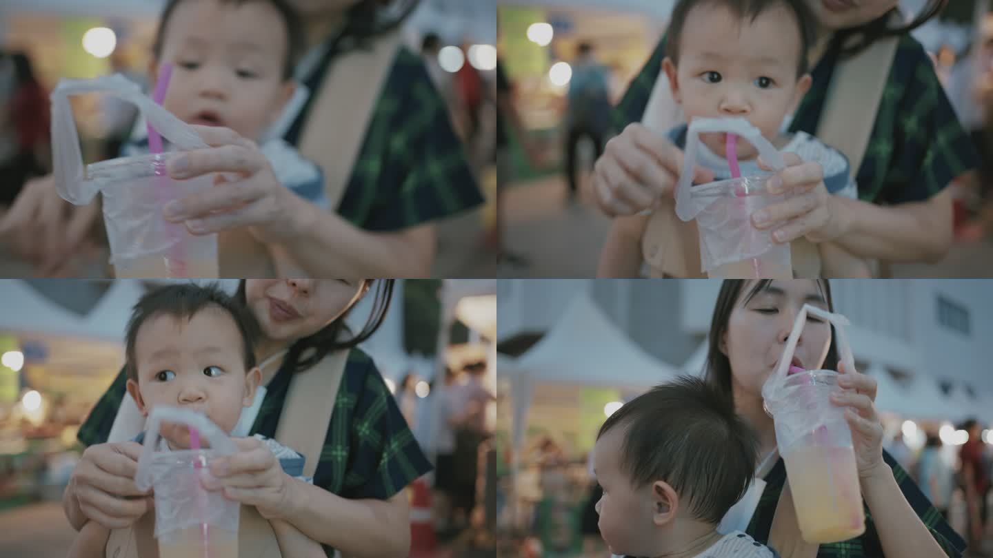 年轻的妈妈在泰国街头食品市场给儿子喂甘蔗汁