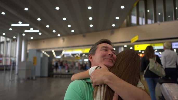 心爱的女儿在机场拥抱她的父亲，而他亲吻她的告别