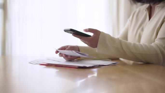 使用智能手机qr或条形码扫描支付家庭财务账单的女性