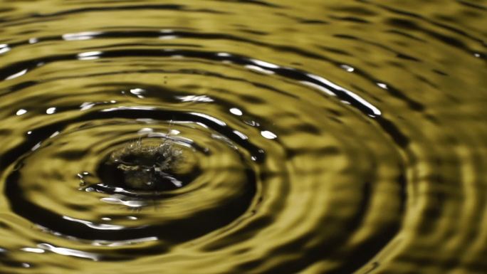 慢动作：许多水滴入黄色水中。