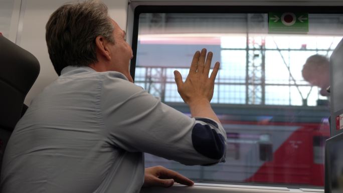 可爱的男孩们跑到窗外，看着爸爸在火车上离开，爸爸挥手告别