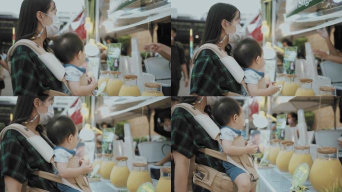 年轻的妈妈和儿子在泰国街头食品市场买甘蔗汁