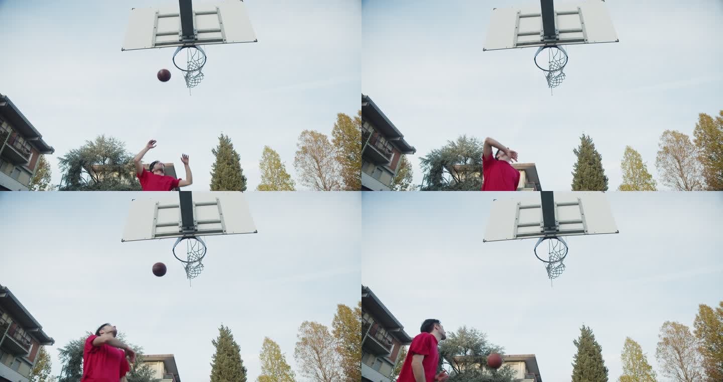 一个年轻的成年男子在篮球场上进球的低角度视图