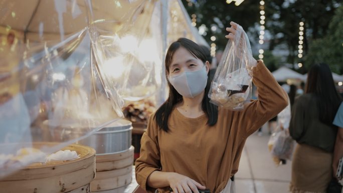 亚洲女游客在泰国街头食品夜市买点心