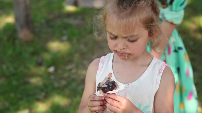 沉思的小女孩在公园里吃冰淇淋