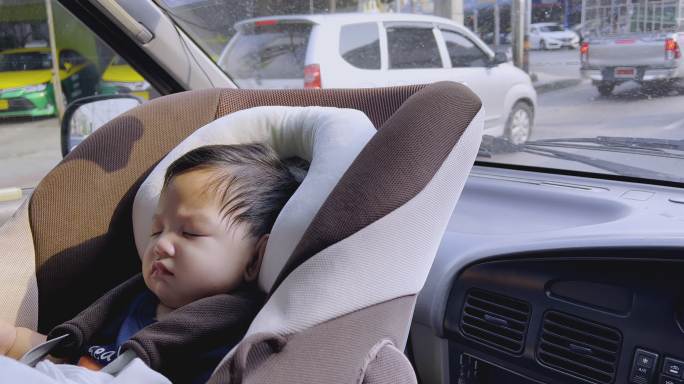 亚洲男婴睡在汽车座椅上，曼谷的城市生活。