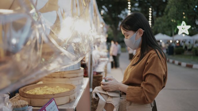 亚洲女游客在泰国街头食品夜市买点心