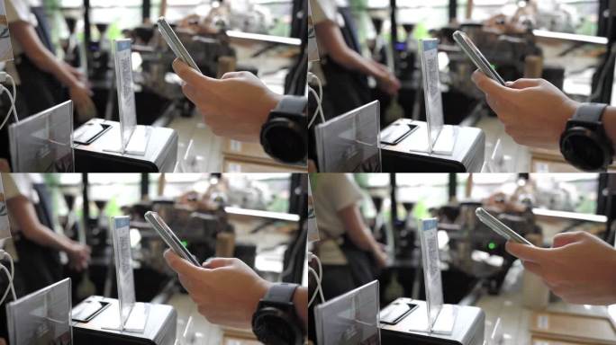 亚洲顾客在咖啡馆柜台使用手机无接触支付。
