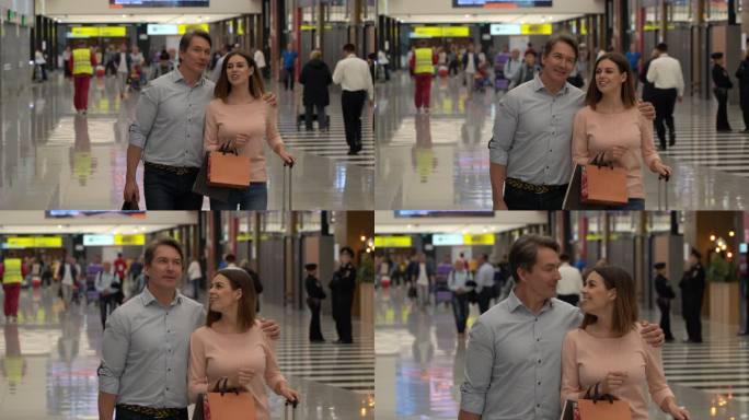 幸福的夫妇拿着免税购物袋在机场边走边聊