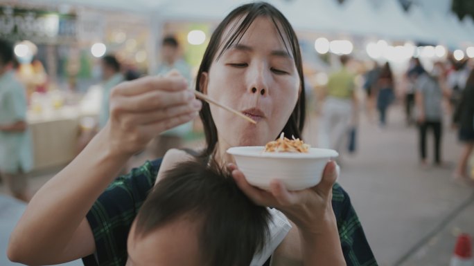 年轻的母亲在泰国享受街头美食