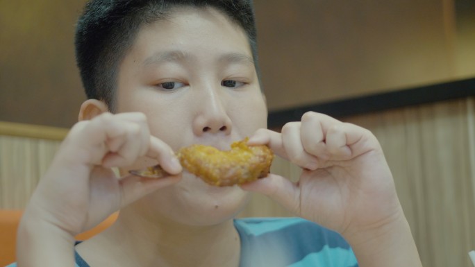 亚洲男孩在快餐店吃炸鸡，带着家庭、生活方式的理念。