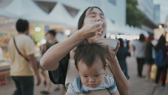 年轻的母亲在泰国享受街头美食