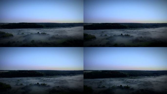 黎明时分被浓雾笼罩的不可思议的山谷、树木和湖泊的长距离空中放大全景