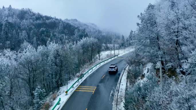 航拍大雪纷飞中公路上行驶的车