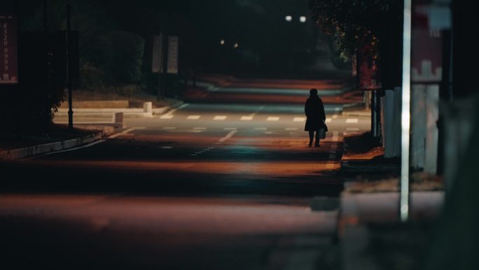 一个人孤独的行走在夜晚的马路街道长焦拍摄