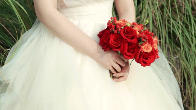 穿着婚纱的姑娘手里的红色玫瑰花束