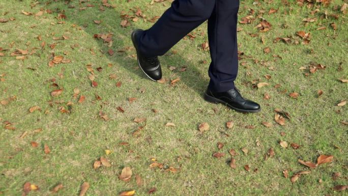 行走在草地上草地上黑色的皮鞋
