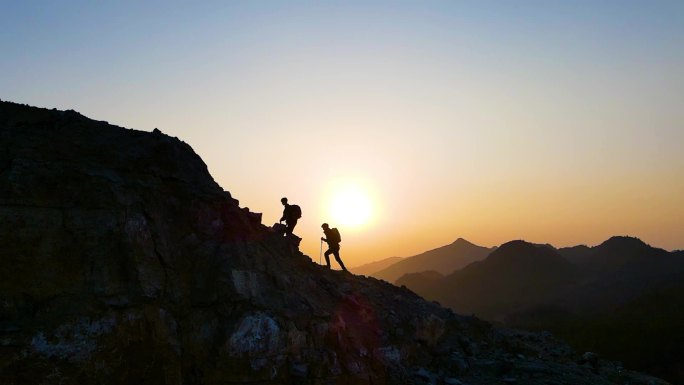 团队登山剪影逆光爬山攀登顶峰展望未来行者