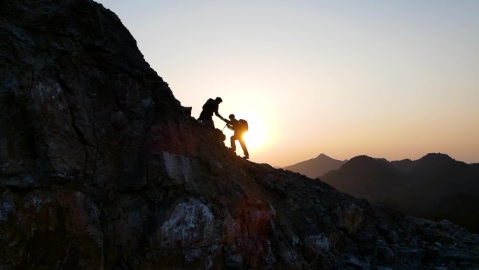 团队逆光登山手拉手成功登顶团队协作攀登者