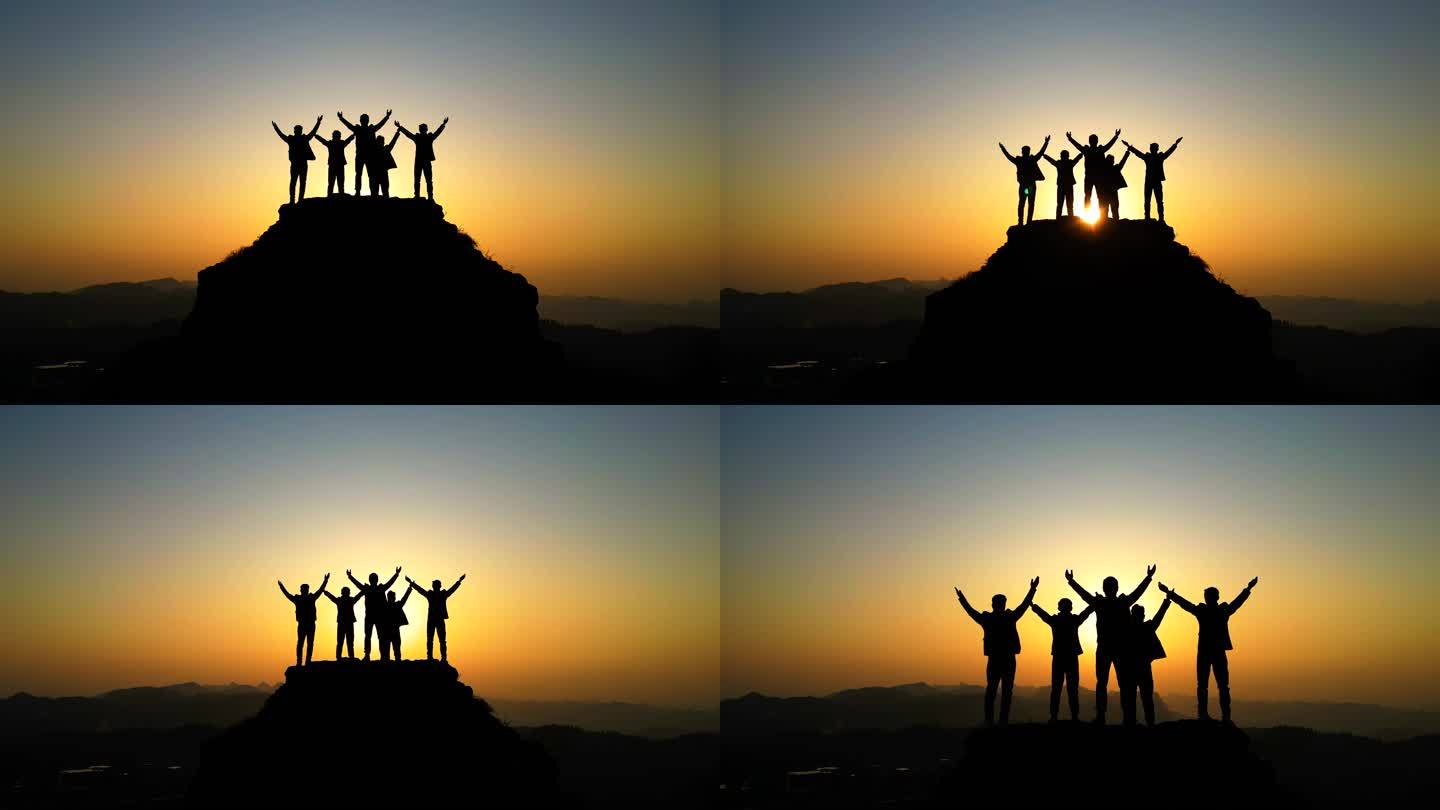 一群人登上山顶站在山顶张开双臂拥抱太阳光
