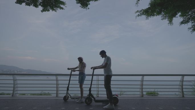 骑滑板车去海边约会的情侣
