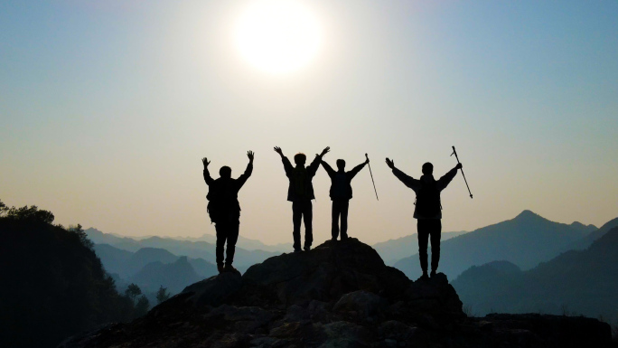 一群人站在山顶眺望远方举手欢呼团队剪影