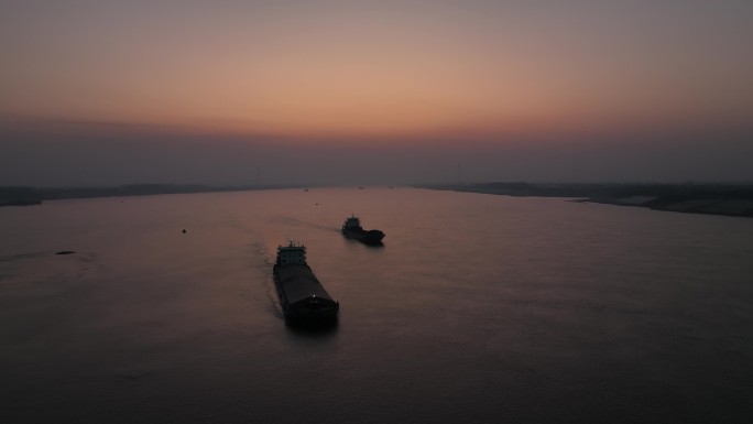 日落余晖下长江江面上跟拍过往的轮船运沙船