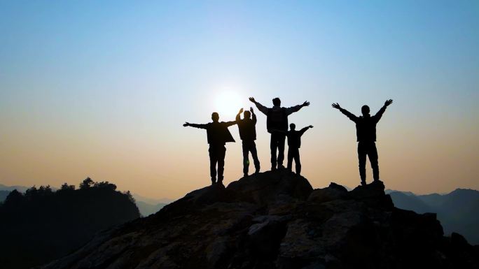 团队山顶举手欢呼拥抱太阳成功登顶团队精神