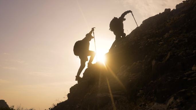 登山登山行者正在迎着阳光逆光成功攀登高峰