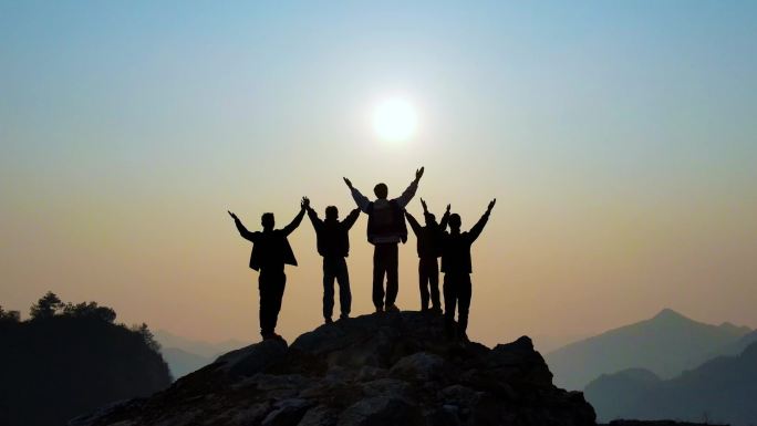一群人山顶举手欢呼张开双臂拥抱太阳攀登者