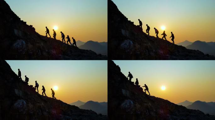 一群人逆光山顶行走剪影团队精神攀登顶峰