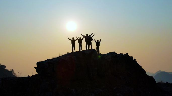一群人站在山顶举手欢呼眺望远方成功登顶
