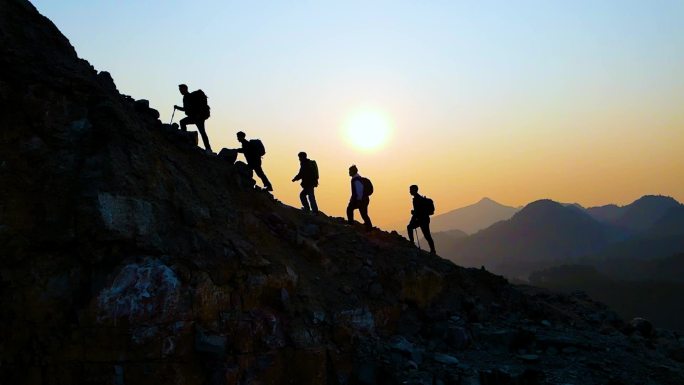 团队爬山剪影登山运动团队逆光行走攀登山峰