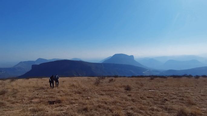 登山客行走在层峦叠嶂的山顶草原