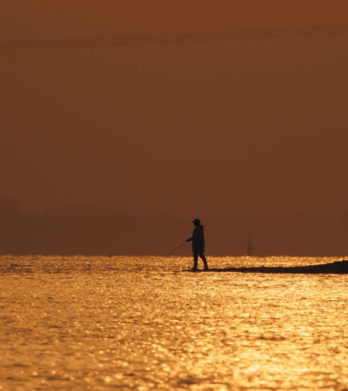 长江边橙色的夕阳下钓鱼者甩竿钓鱼竖屏