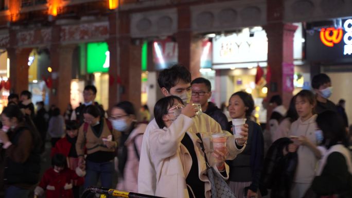 夜晚泉州西街上一对情侣游客在拍照打卡地标