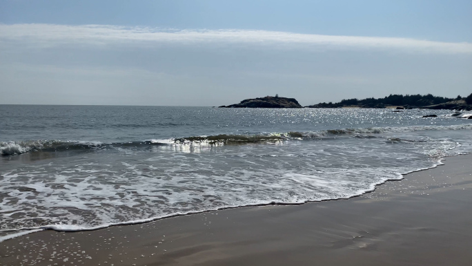 海边沙滩上的浪花拍打礁石