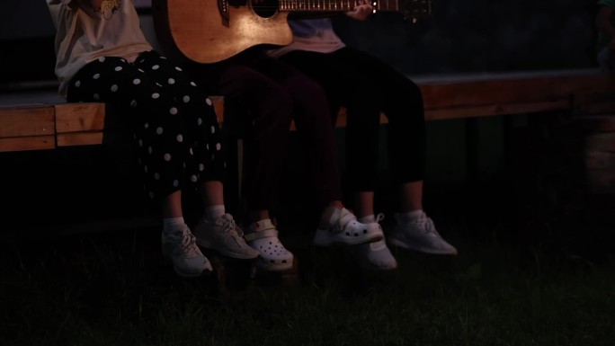 晚上野外露营弹吉他唱歌的青春女生
