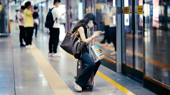 坐在行李箱等地铁的女子