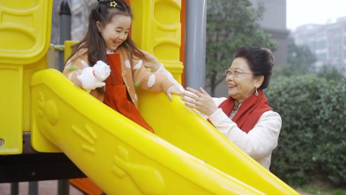 奶奶陪伴孙女幸福玩耍做游戏户外滑滑梯