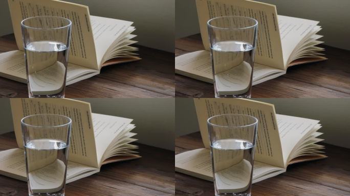 一杯水和一本翻开的书放在桌子上
