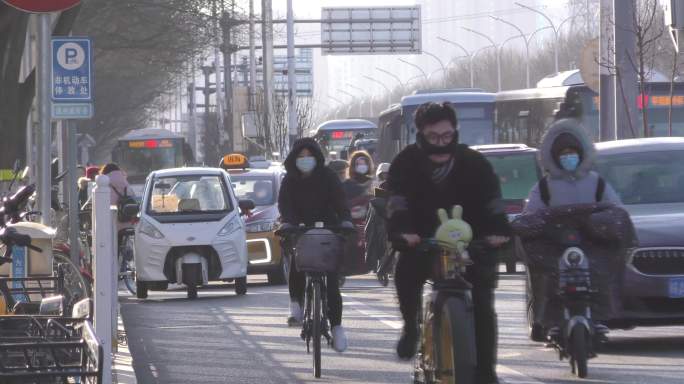 冬天城市骑电瓶车的过马路的行人城市上班族