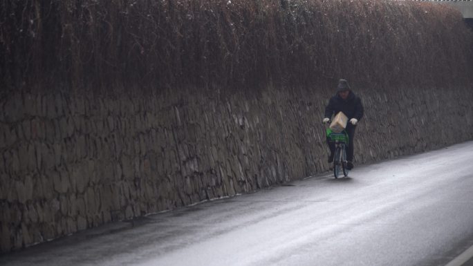 冬季一位戴着帽子的老人骑车自行车经过